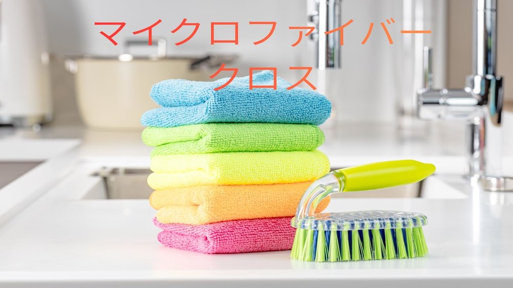 机の上にブラシの他に、下からピンク、オレンジ、イエロー、ライトグリーン、スカイブルーの鮮やかなマイクロファイバークロスが積み上げられている様子。